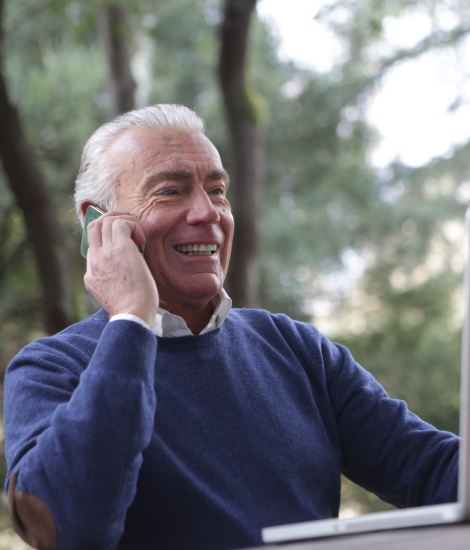 A happy older man talking on the phone while on a telephone consultation with Real Life Care