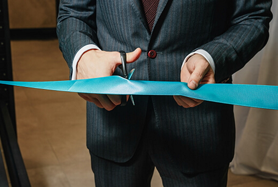 Someone in a suit cutting a ribbon, symbolising a local council agreeing funding for a patient