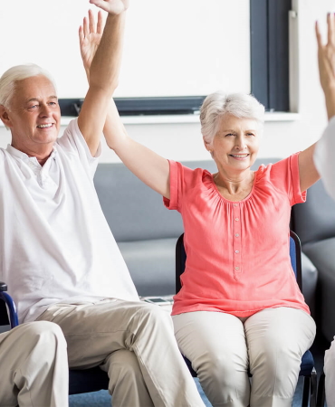 Some very happy older people say in a care home with their arms in the air as they have just won a refund for overpaid care fees
